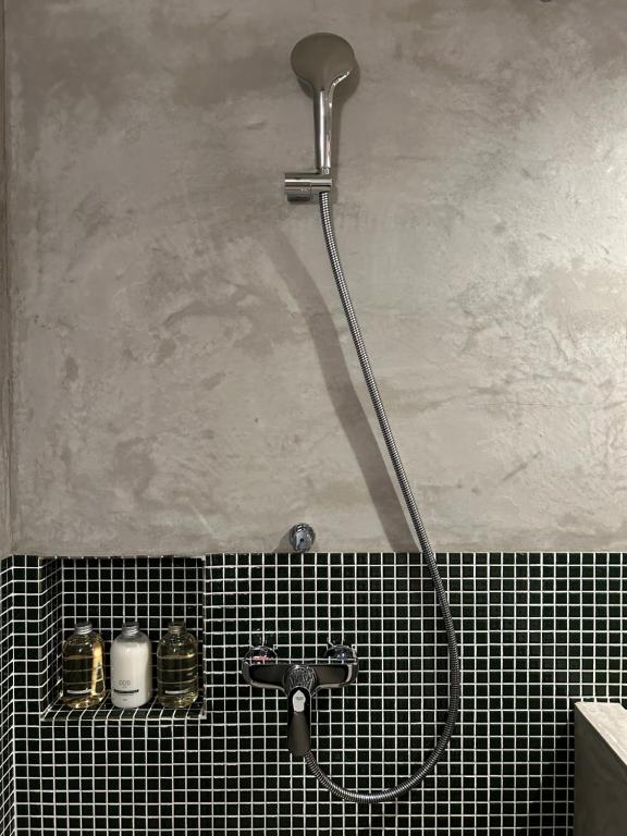 松山市にあるグループに最適The Bath & Bed Dogo 築110年の蔵をリノベした源泉掛け流し一棟貸しの温泉宿のバスルーム(タイル張りの壁にシャワーヘッド付)