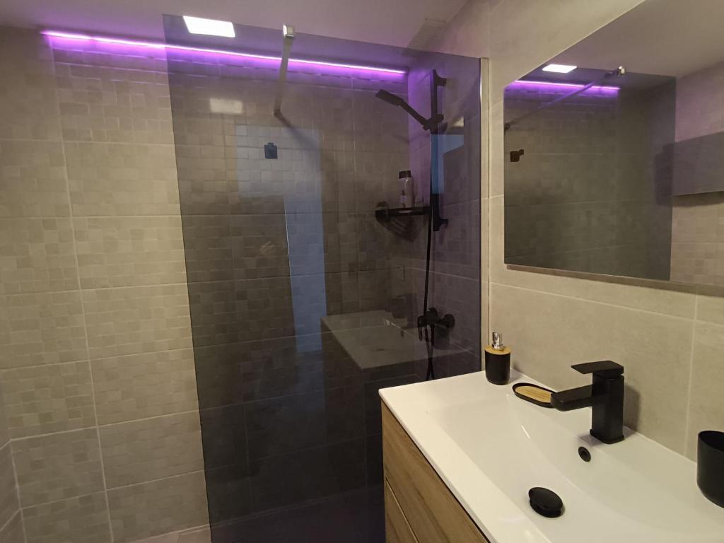 ein Badezimmer mit einem Waschbecken und einer Dusche mit violetten Lichtern in der Unterkunft Apartamento SUN Complex Amaya Fuerteventura in Costa de Antigua