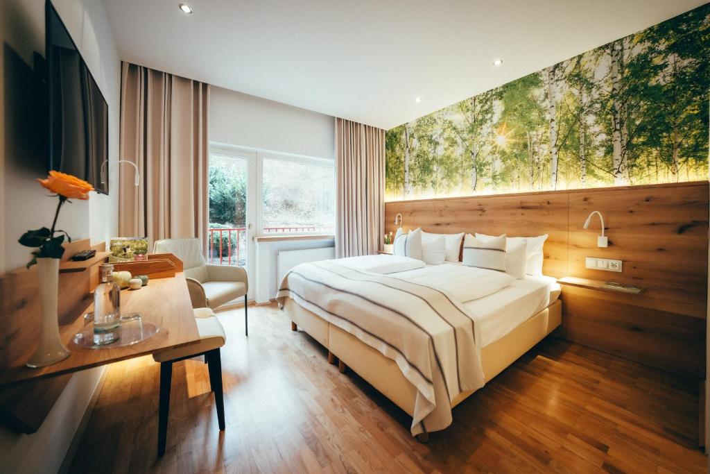 a hotel room with a large bed and a desk at Landidyll Hotel Weidenbrück & SPA in Swisttal