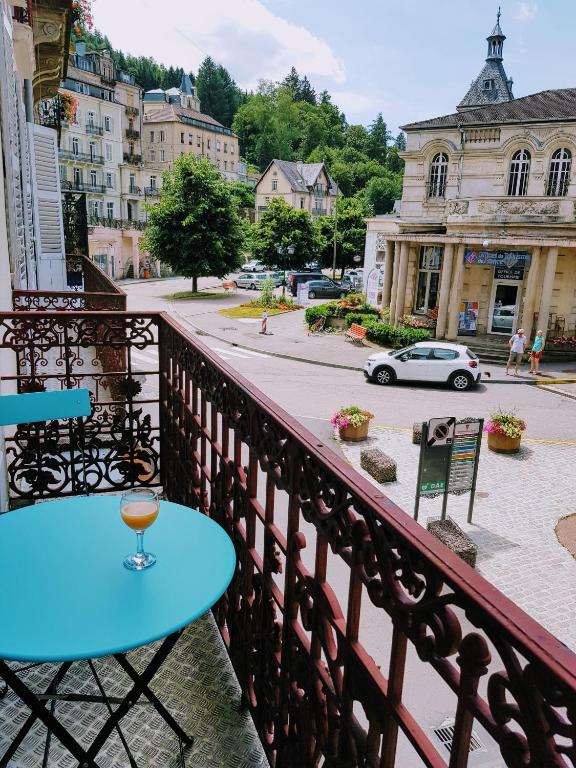 une table bleue sur un balcon avec une rue dans l'établissement Tradition Plombières, à Plombières-les-Bains
