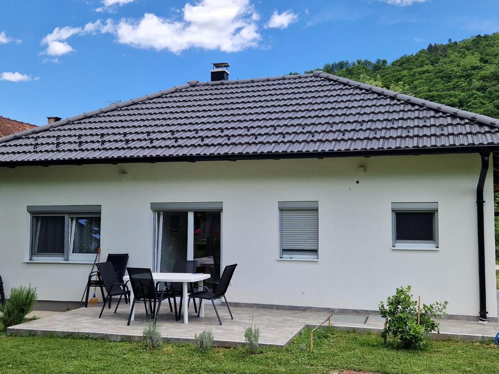 a white house with a table and chairs at Sofija, Guests House in Ključ