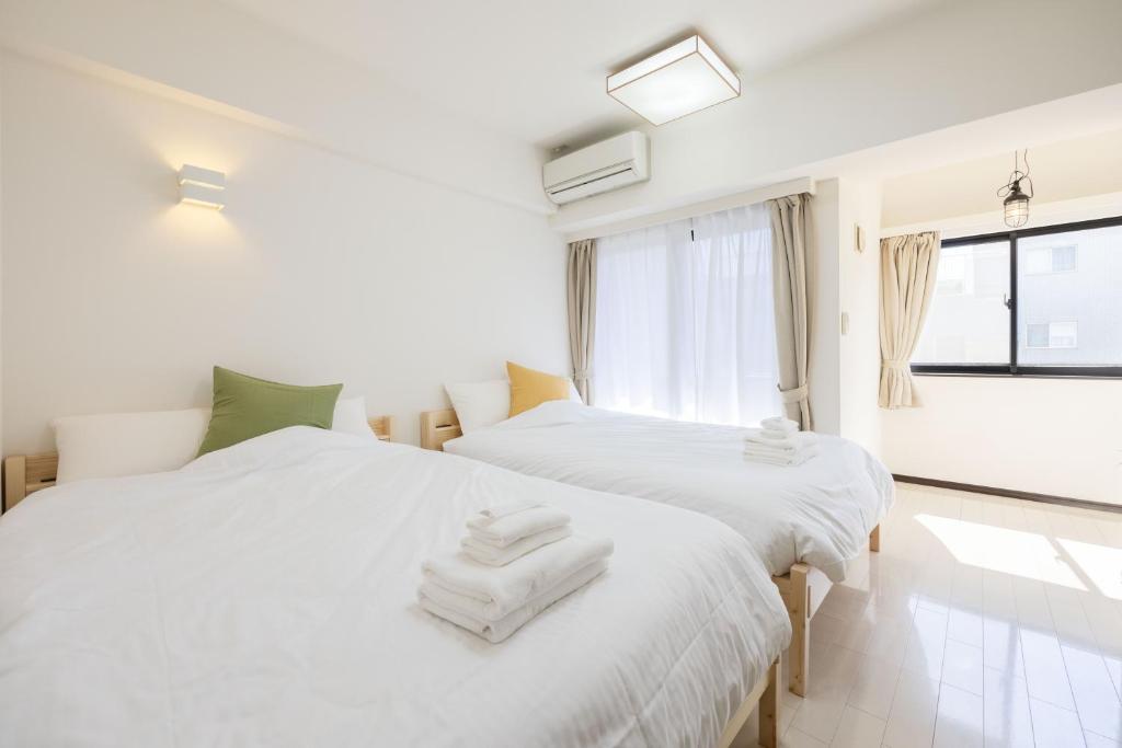 2 witte bedden in een kamer met een raam bij Skytree View Kinshicho - Self Check-In Only in Tokyo