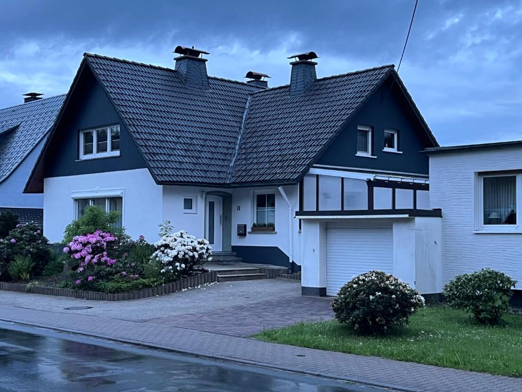 uma casa branca com um telhado preto em Modern und Rustikal mit Kamin Ferienwohnung Kohlert em Bad Berleburg