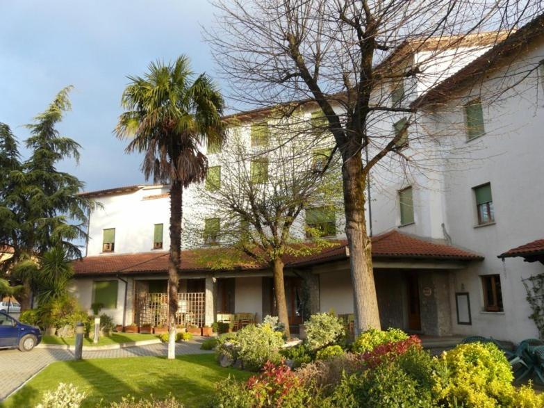 a large white building with palm trees in front of it at Hotel La Piccola Stazione in Torrita di Siena