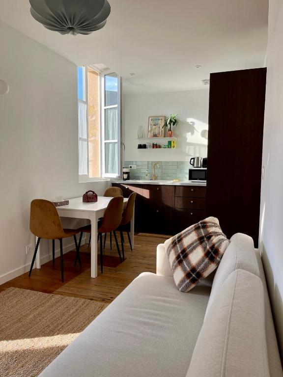 ein Wohnzimmer mit einem weißen Sofa und einem Tisch in der Unterkunft Montfaucon - Élégant appartement & terrasse au cœur de Bordeaux, idéalement situé in Bordeaux