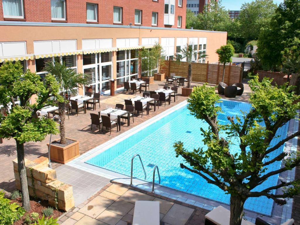 una vista aérea de una piscina con mesas y sillas en ibis Hotel Hannover Medical Park en Hannover