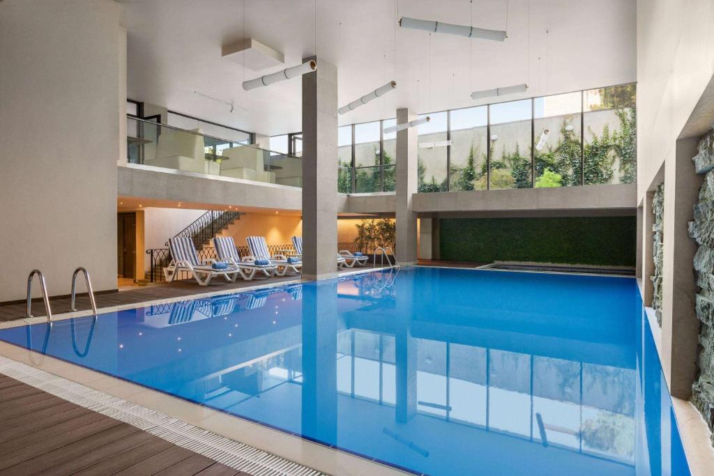 a large swimming pool in a building with a house at Ramada by Wyndham Tbilisi Old City in Tbilisi City