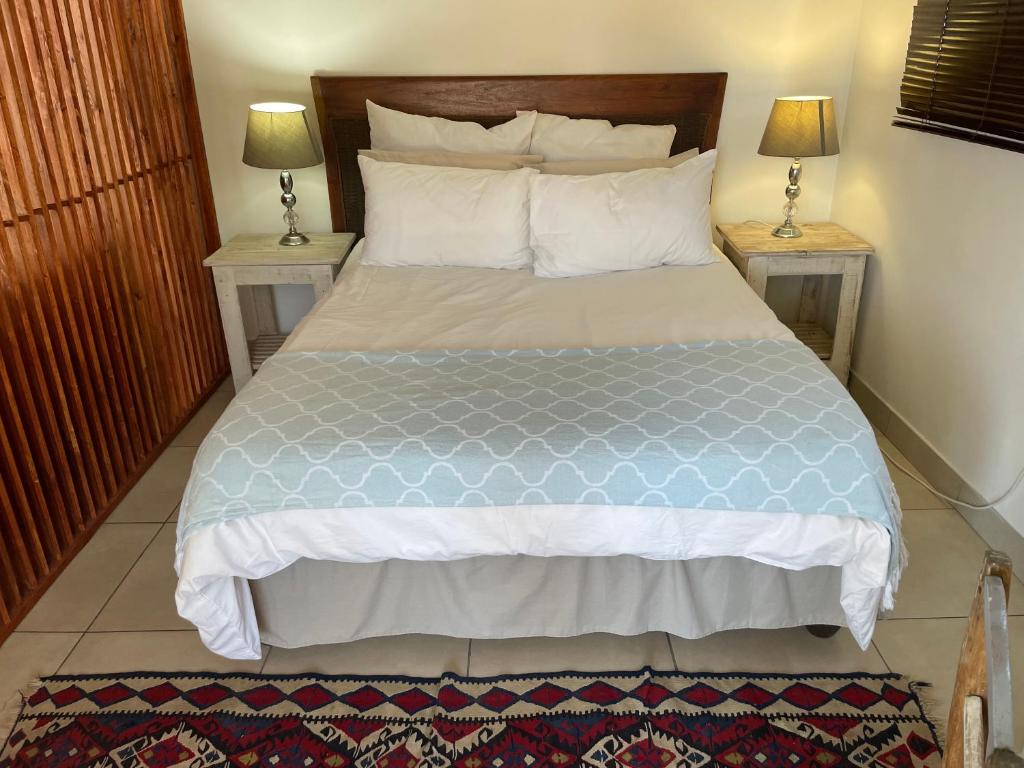 a bedroom with a bed with two nightstands and two lamps at Supertubes Apartment in Jeffreys Bay