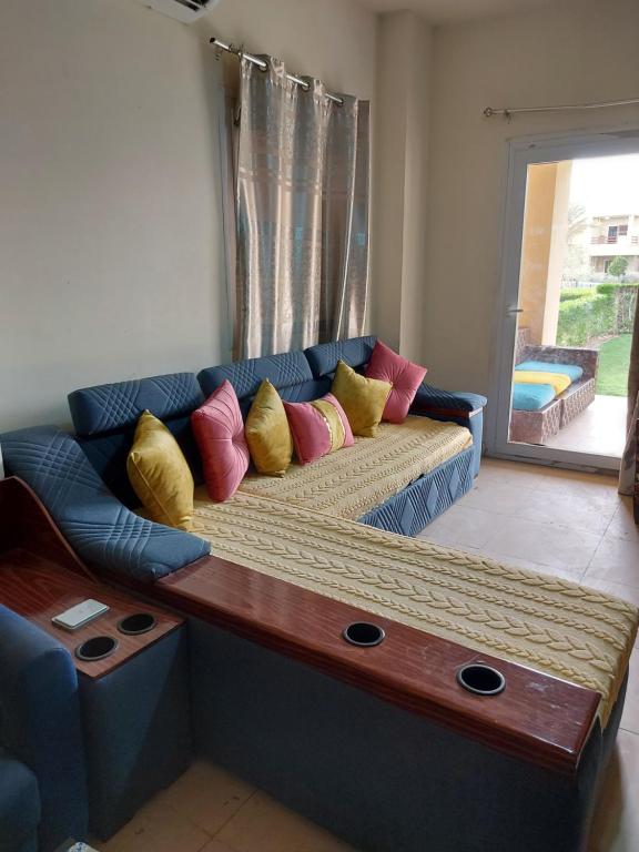 um sofá azul com almofadas coloridas numa sala de estar em Mousa Coast aquapark view chalet with garden em Ras Sedr