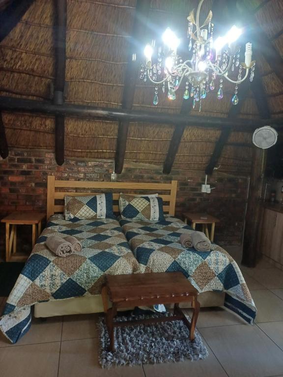 een slaapkamer met een bed en een kroonluchter bij WHY NOT GUESTHOUSE in Bothaville