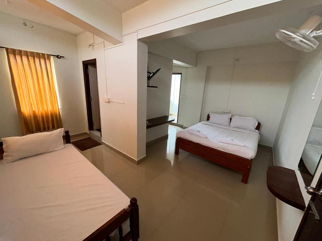 1 Schlafzimmer mit 2 Betten und einem Fenster in der Unterkunft HOTEL CHRUCH SIDE in Madikeri