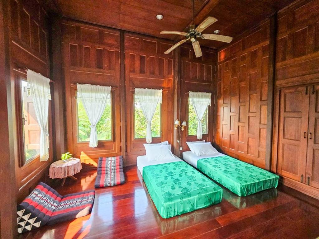 2 Betten in einem Zimmer mit Holzwänden und Fenstern in der Unterkunft The Thai House Homestay & Thai Cooking Experiences in Ban Bang Sano