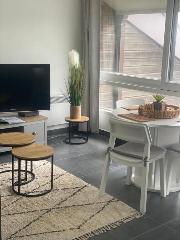 uma sala de estar com uma mesa branca e uma televisão em Jetez l'ancre à la marina de deauville em Deauville