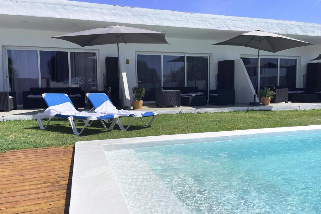 twee stoelen en parasols naast een zwembad bij Agoodplan Dehesa de El Palmar in Cádiz