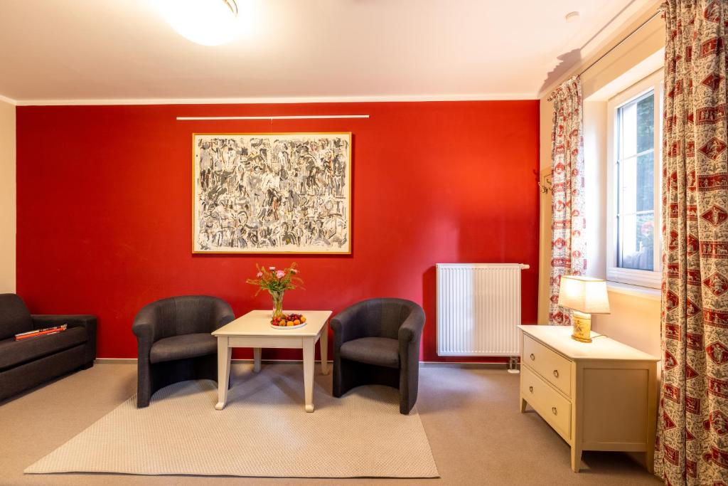 - un salon avec des murs rouges, une table et des chaises dans l'établissement Café Wildau Hotel & Restaurant am Werbellinsee, à Schorfheide