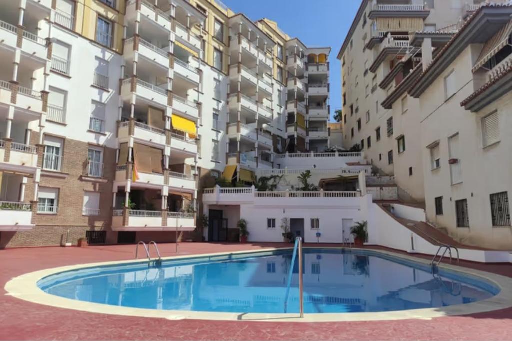 uma grande piscina num pátio em frente a edifícios de apartamentos em "La Casita de Sal" cerca de la playa, con piscina comunitaria y wifi em La Herradura