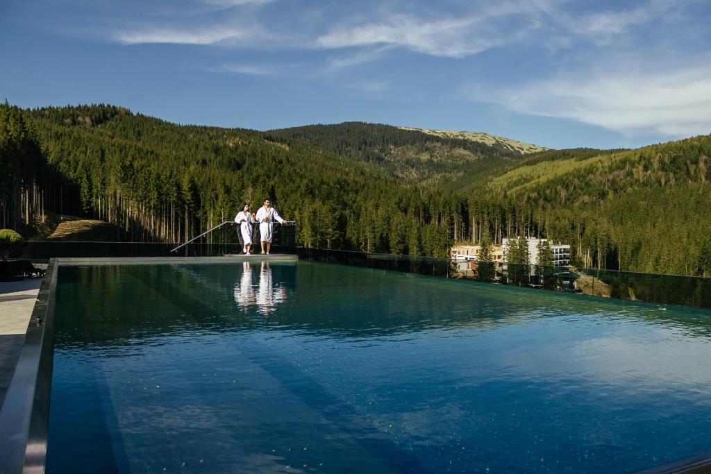 dos personas de pie en el borde de un charco de agua en Rest&Ski Spa Resort, en Bukovel