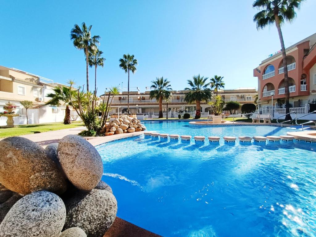 a swimming pool at a resort with palm trees at Sunny Blue Home - near Pools, Beach and Golf in Los Alcázares