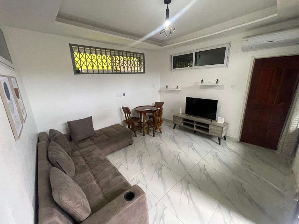 uma sala de estar com um sofá e uma mesa em Confortable 2 bedrooms - Center of Osu noble house em Acra