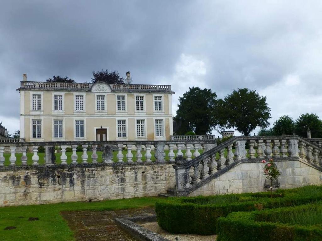 uma grande casa branca com uma parede de pedra e uma ponte em Le Chai, Chateau de Charras, Family Friendly Holiday Destination em Charras