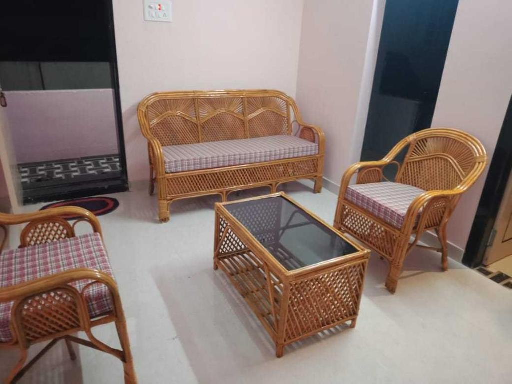 a group of wicker chairs and a table in a room at OYO HOME 81185 Srinivas Service Home in Rājahmundry