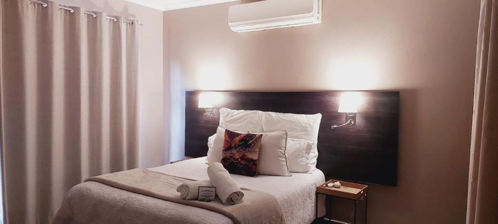 1 dormitorio con 1 cama con cabecero negro y almohadas blancas en Modern Home Accommodation, en Zeerust