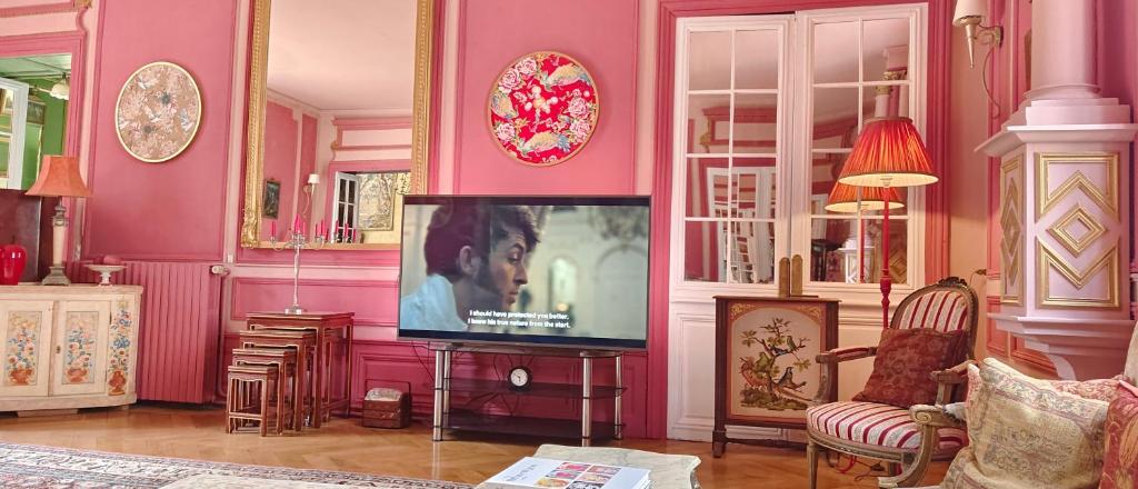 a living room with pink walls and a flat screen tv at Chateau de la Grand'Maison in Bellême