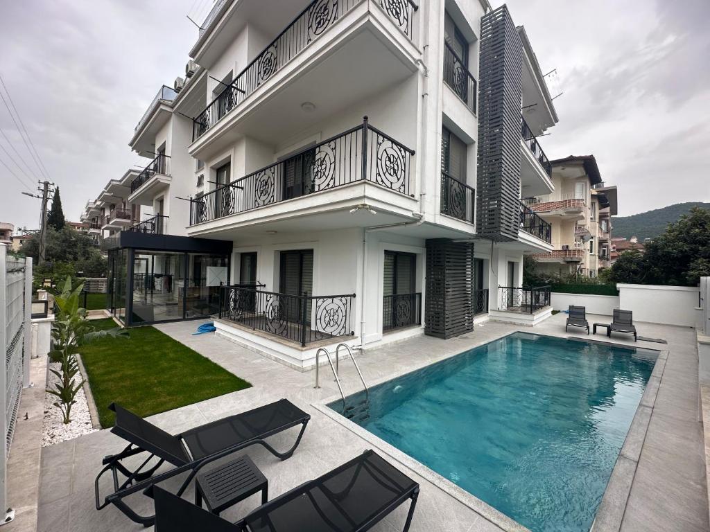 une villa avec une piscine en face d'un bâtiment dans l'établissement Arti̇m Apart Hotel, à Fethiye