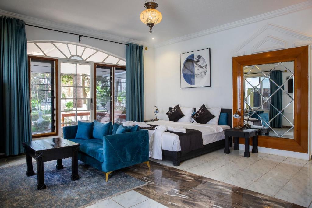 een slaapkamer met een bed en een blauwe bank bij Coconut Residence & Spa in Kololi