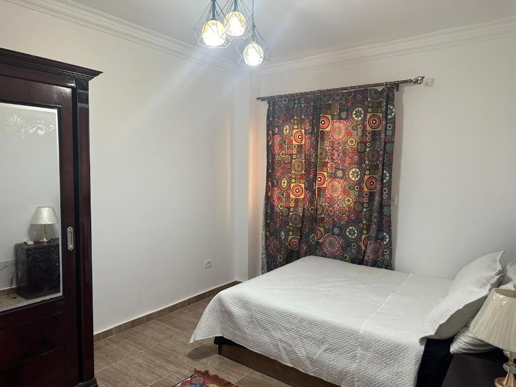 a bedroom with a bed and a colorful curtain at Quite apartment with positive vibes in New cairo