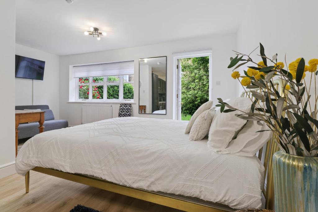 um quarto com uma cama branca e um vaso de flores em Finsbury Park Studios em Londres