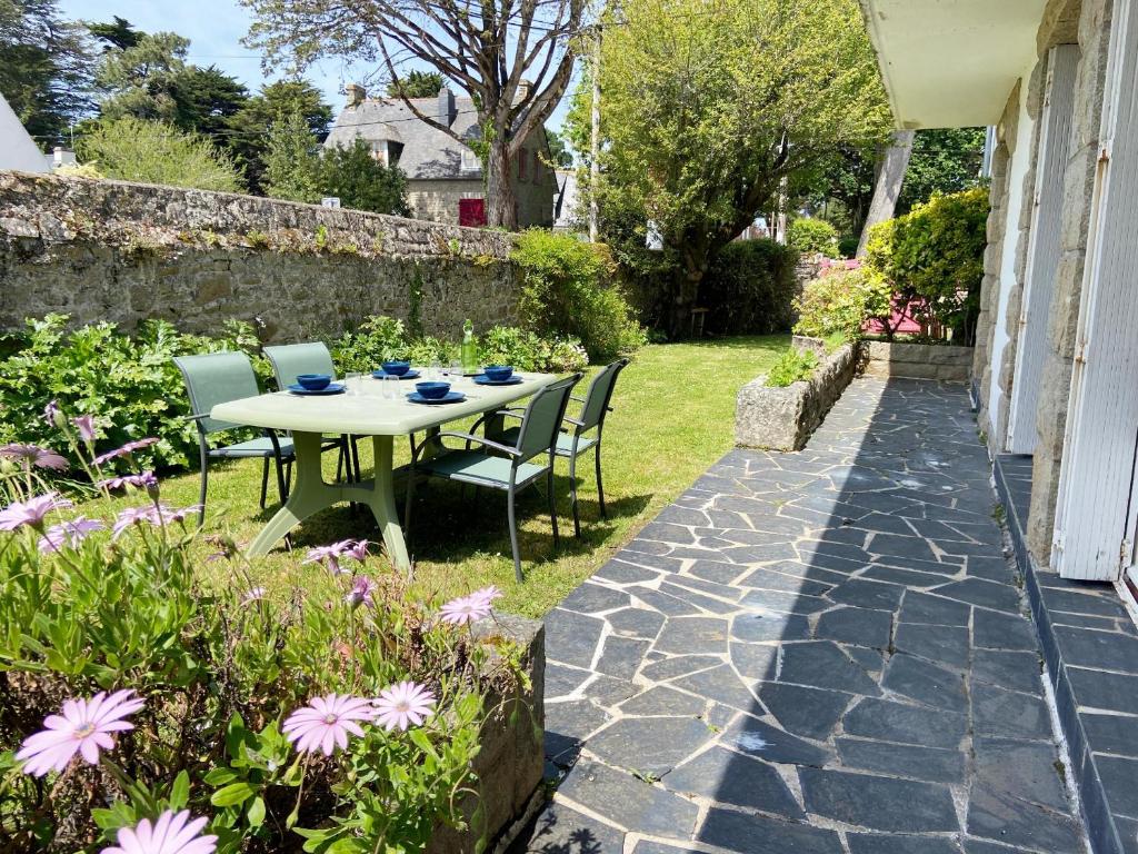 une table et des chaises dans un jardin fleuri dans l'établissement ARVOR 3 - Rez-de-jardin, Terrasse, Plage - T40, à Carnac