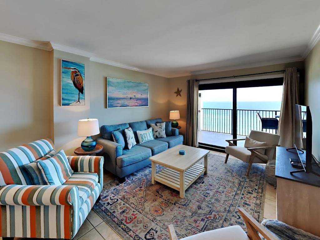 a living room with a blue couch and a table at Ocean Breeze East #802 in Perdido Key