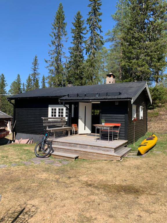 a black cabin with a deck and a table at Gilleråsvägen 13 B in Sälen