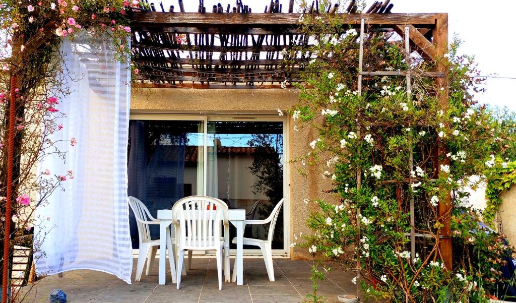 une table et des chaises sur une terrasse avec pergola dans l'établissement Maison de village - triangle NIMES - UZES - ALES, à Moussac