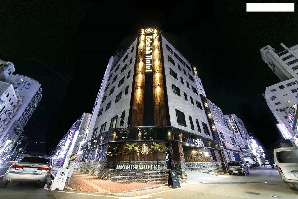 um edifício branco alto com luzes acesas à noite em Heimish Hotel em Tongyeong