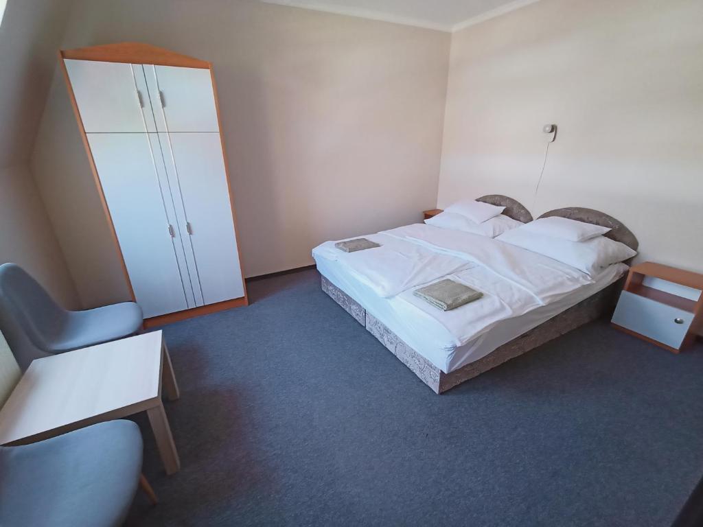 a bedroom with a bed and a cabinet and a chair at AMRI Apartman in Balatonföldvár