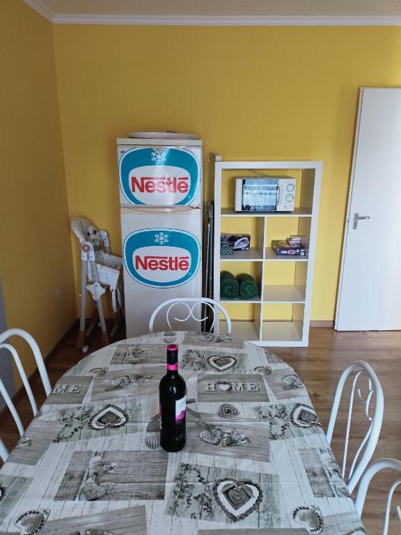 a table with a bottle of wine next to a refrigerator at AMRI Apartman in Balatonföldvár