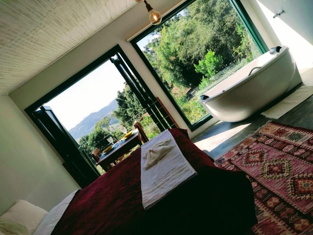 1 dormitorio con bañera, cama y ventana en Montanha Home en Monte Verde