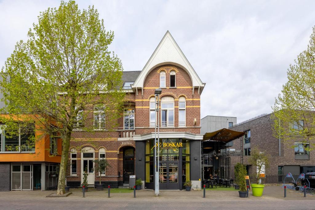 a brick building with a pointed roof on a street at Hotel De Boskar Pelt in Overpelt