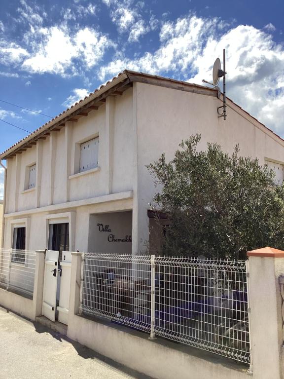 une maison blanche avec une clôture devant dans l'établissement Villa Chemakhi 10 personnes, à Narbonne