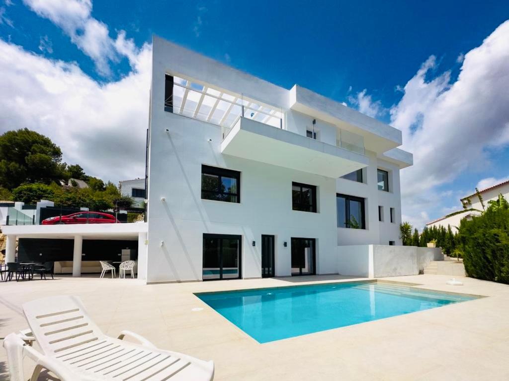 una casa blanca con piscina frente a ella en Calpe villa lujo playa piscina jardin barbacoa ideal familias y grupos, en Calpe