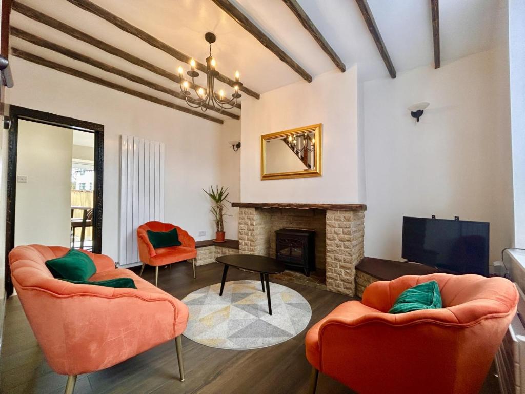 uma sala de estar com cadeiras laranja e uma lareira em CHARLES STREET - Cottage at the edge of the Peak District National Park, Buxton em Buxton