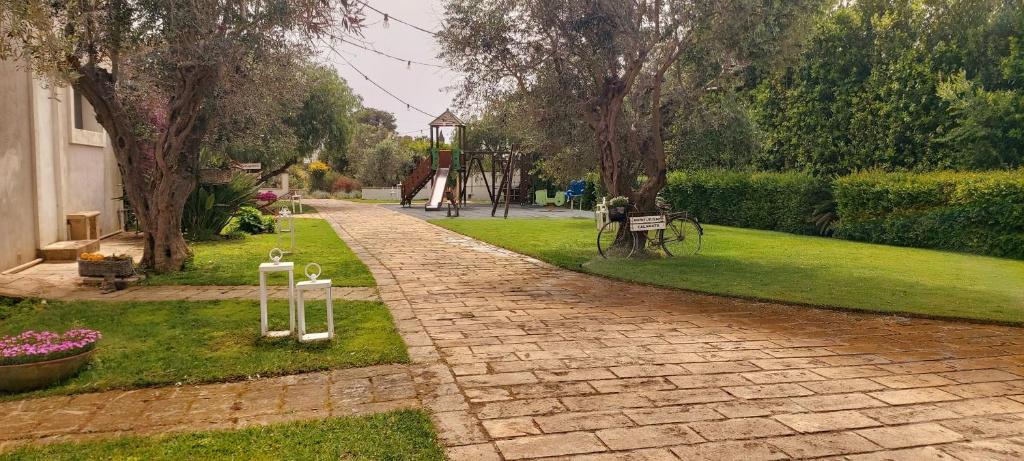 einen Backsteinweg in einem Park mit Bäumen und Gras in der Unterkunft Agriturismo Calamate in Gallipoli