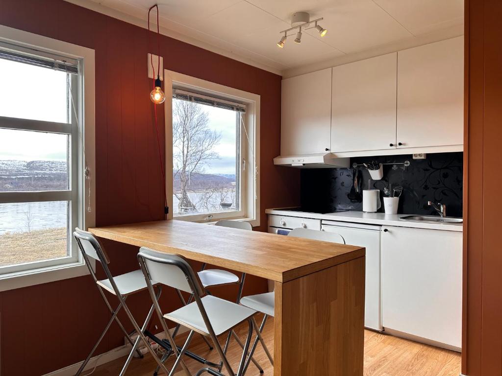 a kitchen with a wooden table and two chairs at Tana Panorama Apartments in Skiippagurra