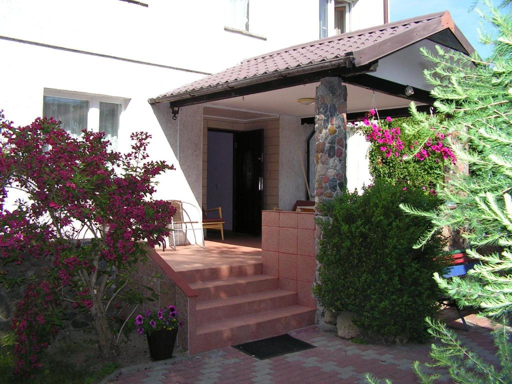 a house with a porch with stairs and flowers at UPaniAni in Ustronie Morskie