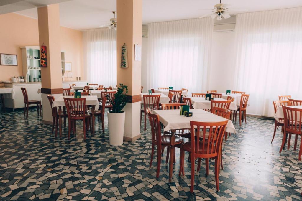 a dining room with tables and chairs in a restaurant at Hotel Enna Rimini in Rimini