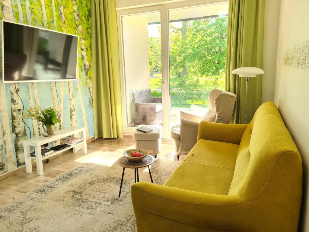 sala de estar con sofá amarillo y TV en Żurawie gniazdo, elegancki zakątek w Puszczy Białowieskiej, en Hajnówka