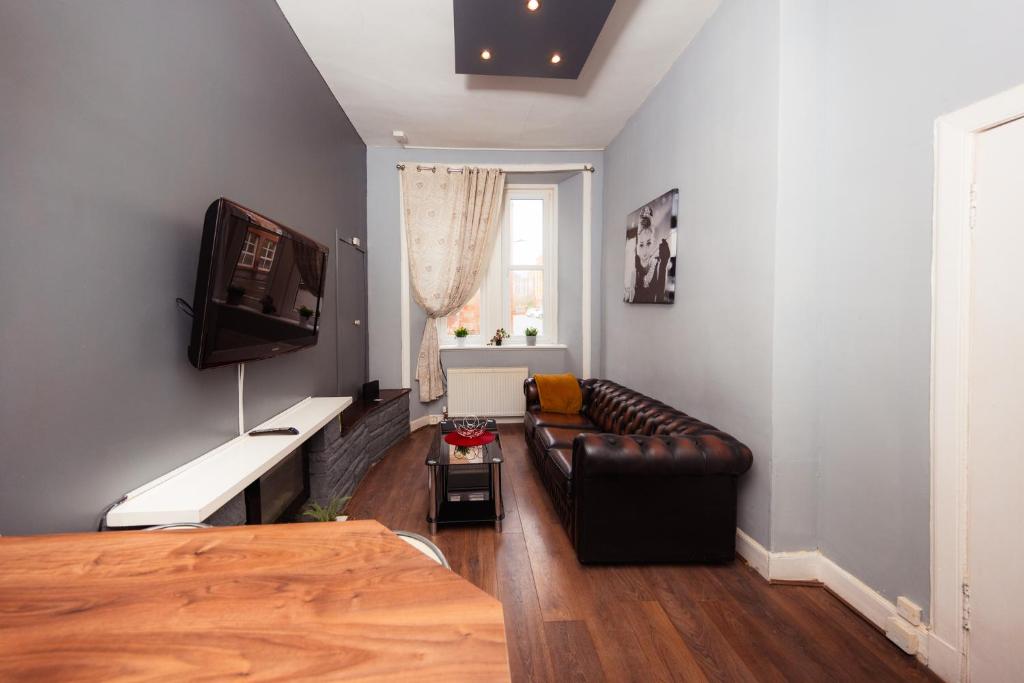 sala de estar con sofá de cuero y TV en Warm 1 Bed Apartment by Holyrood Palace and Park!, en Edimburgo