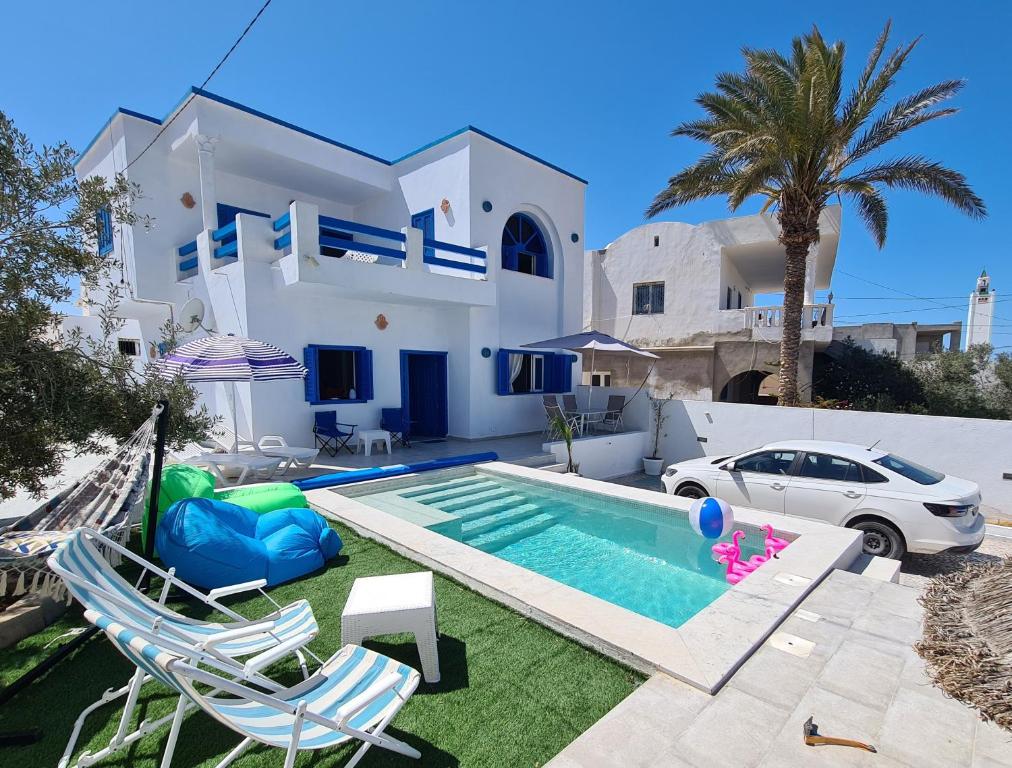 une villa avec une piscine en face d'une maison dans l'établissement Villa Bleue plage Sonia, à Zarzis